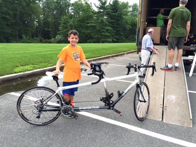 Henry Garnich, whose parents own Knapp's Cyclery, helps load a tandem bike on a truck Thursday night at Timberlane Middle School. 